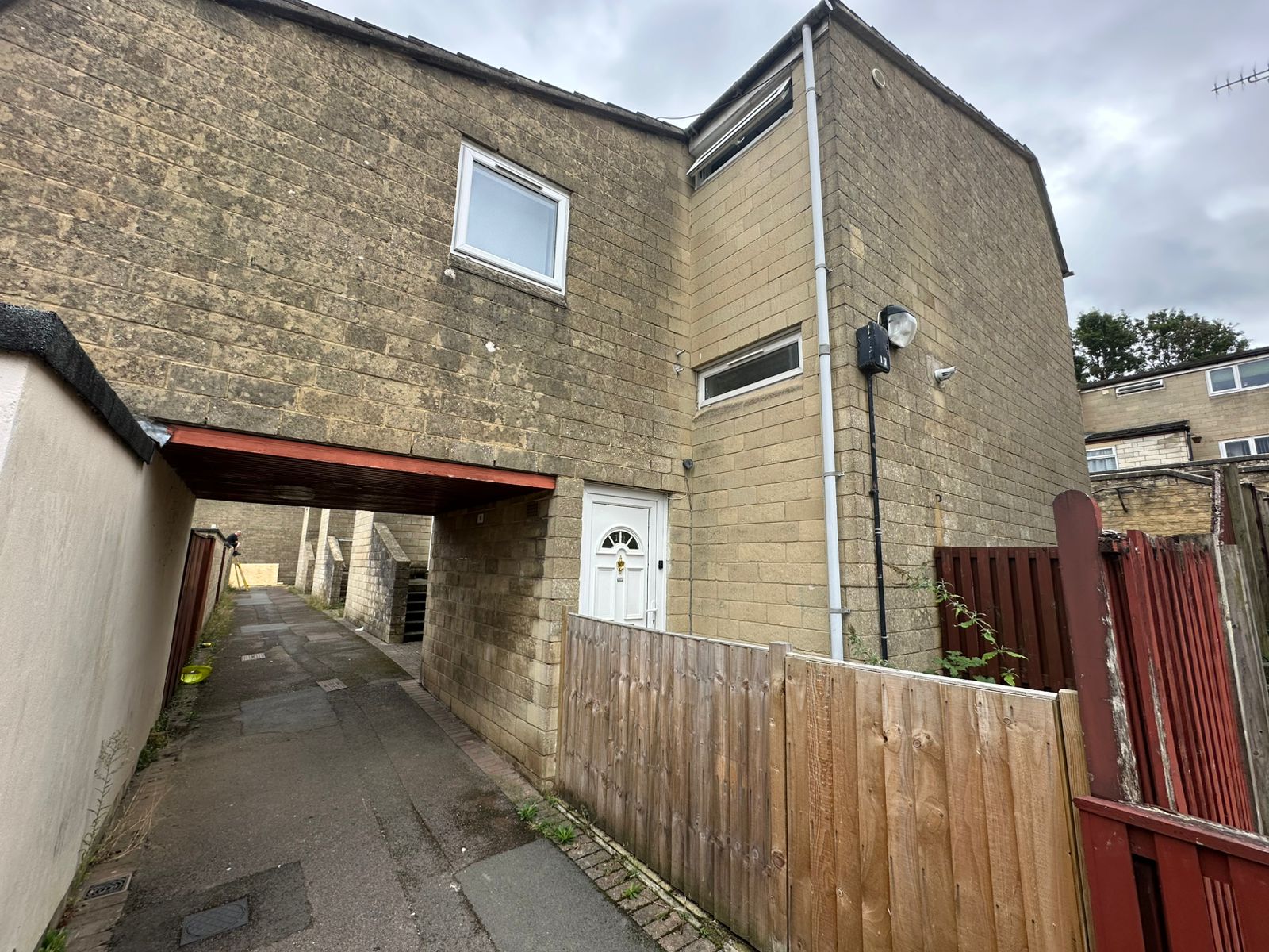 Front of 12 Rooksbridge Walk, pale stone with a white door and a covered passageway