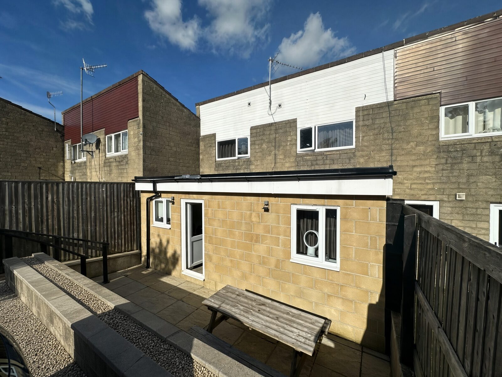Rear of the house with paved garden, patio seating and timber fencing